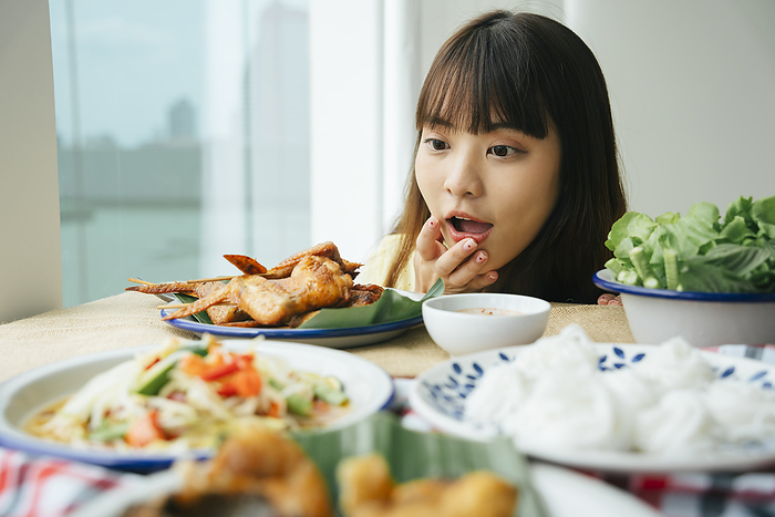 Portrait of young asian woman looking at Isan food on a table with amazed expression.