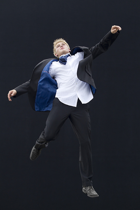 masculine gender Caucasian man in suit jumping in mid air