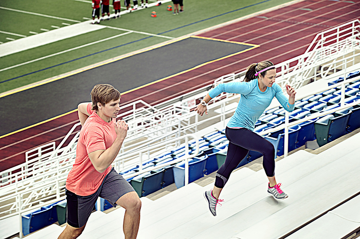 couple Caucasian athletes running up bleachers