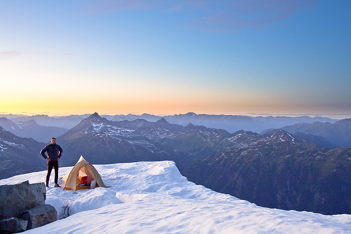 Whistler Canada Climber standing next to tent on mountain summit, Whistler, Canada.