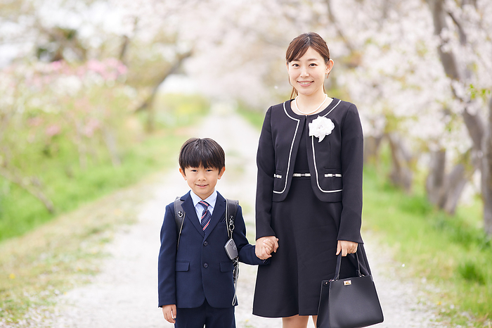 Japanese elementary school boy and his mother with rows of cherry trees