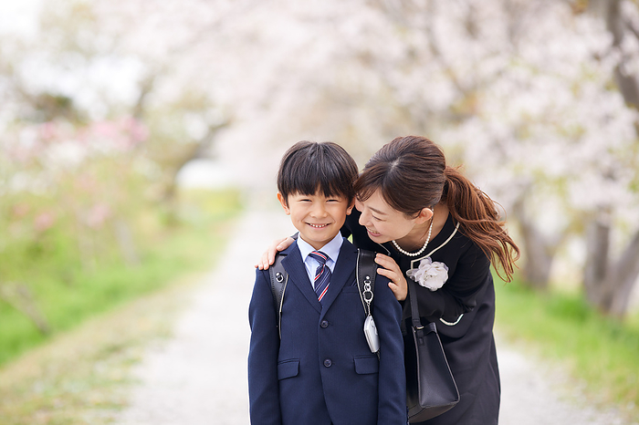 Japanese elementary school boy and his mother with rows of cherry trees