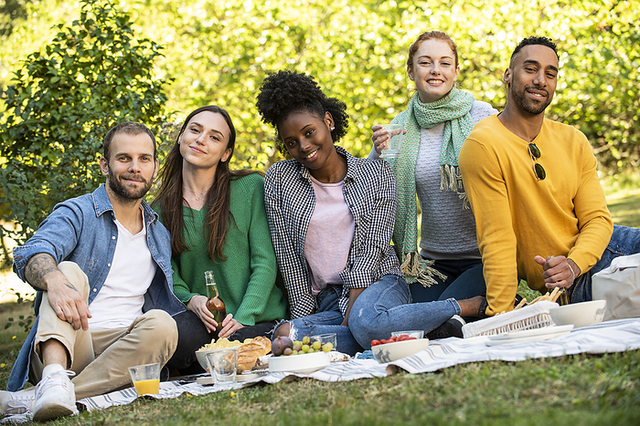 Portrait of smiling young friends having picnic in public park, Photo by Eric Audras
