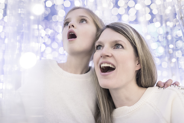 A mother and daughter looking up in wonder with a background of white sparkling lights; Studio, Photo by Don Hammond / Design Pics