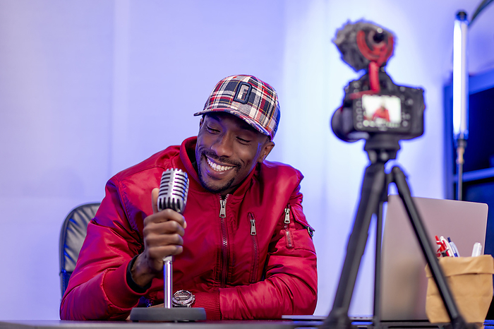 Madrid Spain, funny African man with microphone Smiling male influencer with microphone vlogging in studio, Photo by Oscar Carrascosa Martinez