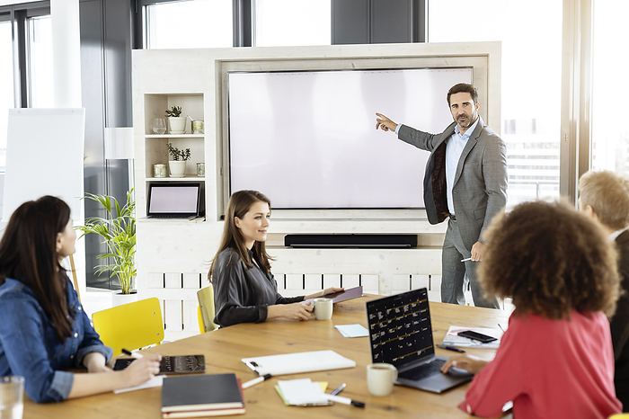Business Male professional pointing at projection screen while working with colleague in meeting