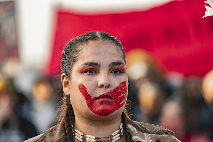 National Day of Mourning on Thanksgiving Day in Plymouth November 25, 2021, Plymouth, Massachusetts, USA: A demonstrator with a red handprint painted over her mouth rallies at  National Day of Mourning  in Plymouth.  A red handprint is a symbol that is used to indicate solidarity with missing and murdered Indigenous women and girls in North America. More than a thousand demonstrators rally to commemorate a  National Day of Mourning  at Plymouth Rock, a symbol of More than a thousand demonstrators rally to commemorate a  National Day of Mourning  at Plymouth Rock, a symbol of disembarkation of the Mayflower Pilgrims, in Plymouth. It s the 52nd year that the United American Indians of New England organizes the event on Thanksgiving Day.