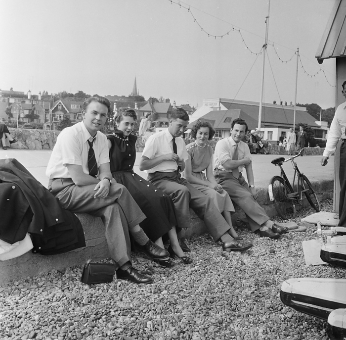 Felixstowe, Felixstowe, Suffolk Coastal, Suffolk, 19 06 1954. Creator: John Laing plc. Felixstowe, Felixstowe, Suffolk Coastal, Suffolk, 19 06 1954. Men and women sitting on a wall beside a gravel beach at Felixstowe during a Laing staff trip. In 1947, after a seven year break, Laing had resurrected their  Area Outings  for staff and their families, with trips taking place in May and June. In 1954, there were seven outings planned to take place over five weeks in May and June. This trip was for employees and their families from the Eastern Counties.