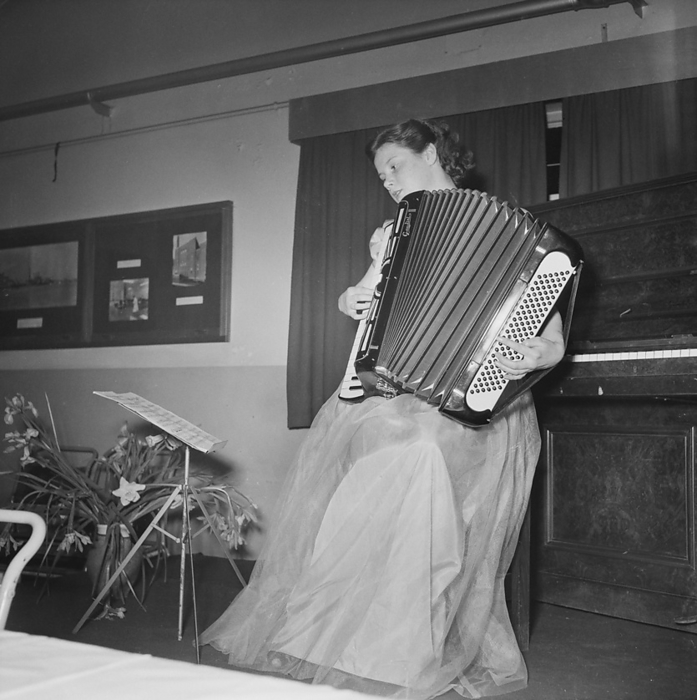 John Laing and Son Limited, Page Street, Mill Hill, Barnet, London, 27 03 1953. Creator: John Laing plc. John Laing and Son Limited, Page Street, Mill Hill, Barnet, London, 27 03 1953. Miss A Hatch playing an accordion at the Sports Club annual dinner. The Sports Club annual dinner was held in the canteen at Laing s Mill Hill office. Following the dinner, entertainment included a piano accordion recital, and concluded with a sing song.