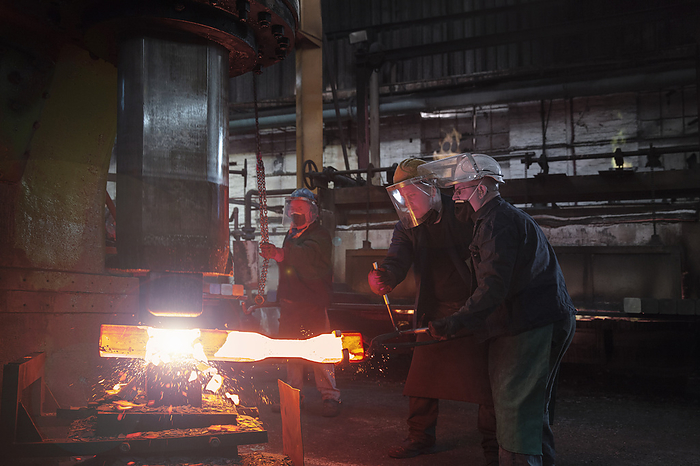 Forge workers pre form red hot steel billet into flight bar  mining component  on hammer Forge workers pre form red hot steel billet into flight bar  mining component  on hammer