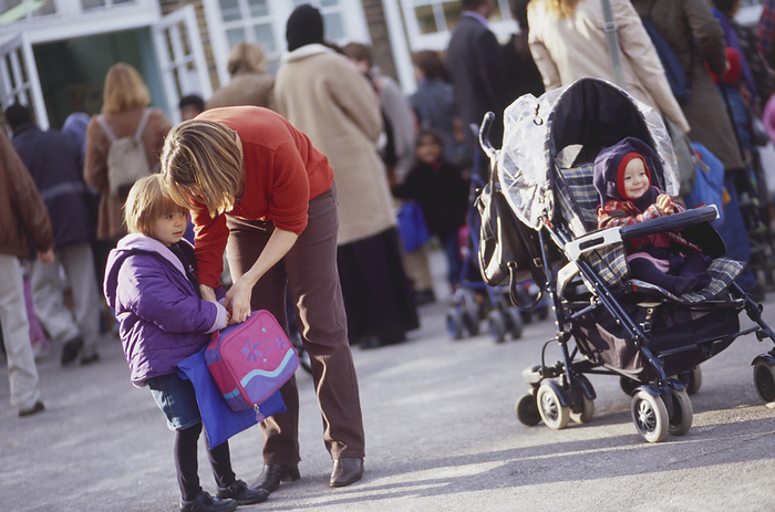 Woman bending over a child carrying a bag Woman bending over a child carrying a bag with a child in a pushchair., Photo by DK IMAGES SCIENCE PHOTO LIBRARY