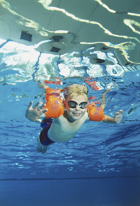 Boy wearing water wings in a swimming pool Boy wearing water wings in a swimming pool., Photo by DK IMAGES SCIENCE PHOTO LIBRARY