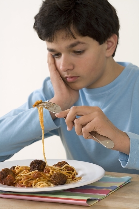 Boy holding fork over plate of spaghetti and meatballs Boy holding fork over plate of spaghetti and meatballs., Photo by DK IMAGES SCIENCE PHOTO LIBRARY