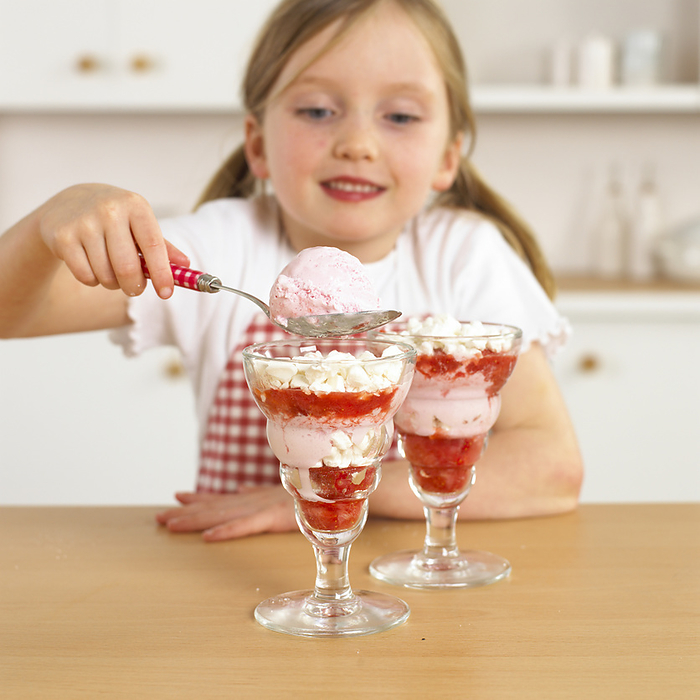 Girl holding spoon of ice cream over glass with ice cream Girl holding spoon of ice cream over glass with ice cream., Photo by DK IMAGES SCIENCE PHOTO LIBRARY