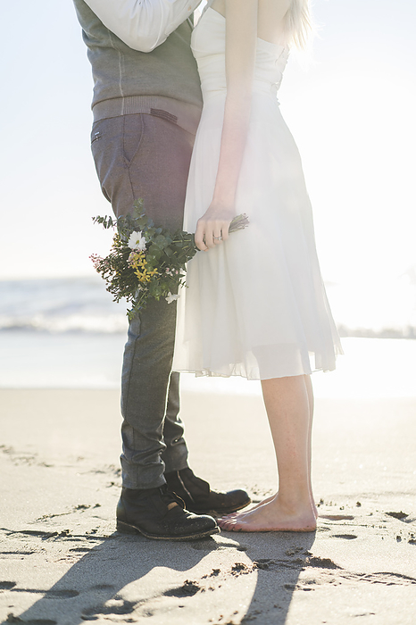 pair of objects, one larger  for man , one smaller  for woman  Newlywed couple standing together on beach