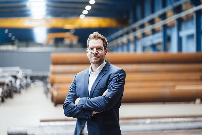 business Businessman standing with arms crossed in industry