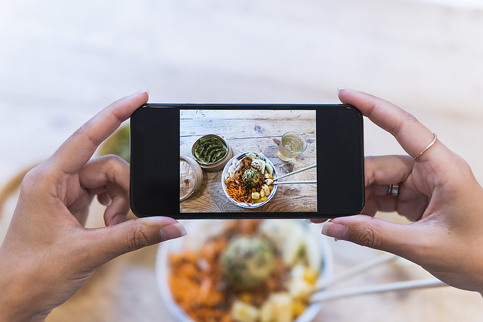 Woman photographing food through smart phone at table