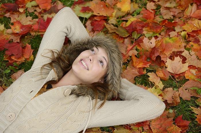 Smiling young woman lying in autumn leaves, Photo by David & Micha Sheldon/F1online