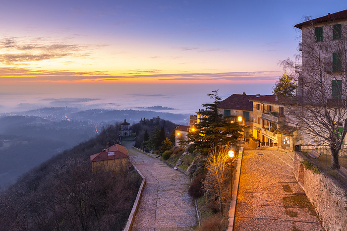 Italy View of the old town of Santa Maria del Monte in winter at sunrise with the fog on Varese city and the Padana plain. Sacro Monte of Varese. Varese, Lombardy, Italy., Photo by Mirko Costantini