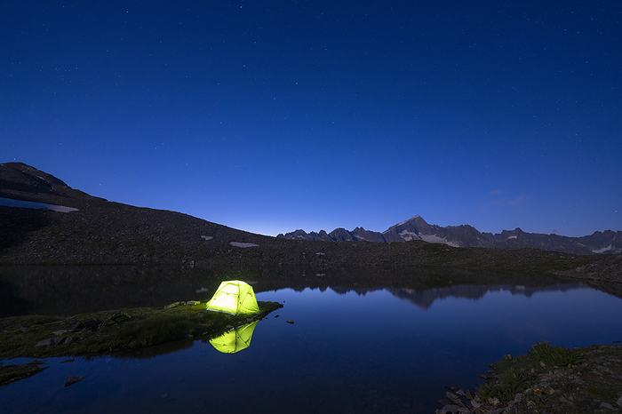 Switzerland Illuminated tent of hiker on shores of  Obere Schwarziseeli lake at night, Furka Pass, Canton Uri, Switzerland, Photo by Roberto Moiola