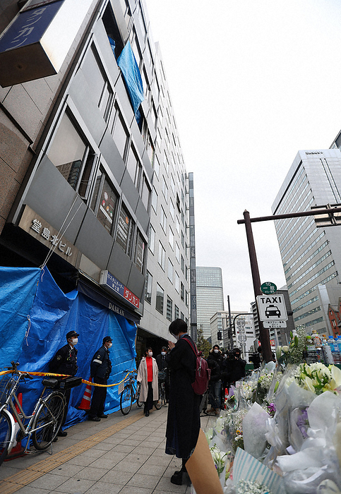 Fire in a building in Kitashinchi, Osaka A woman holds her hands toward the building where an arson murder took place, in Kita Ward, Osaka City, December 2, 2021. Photo by Takeshi Inokai, 2:50 p.m., December 4, 2021.