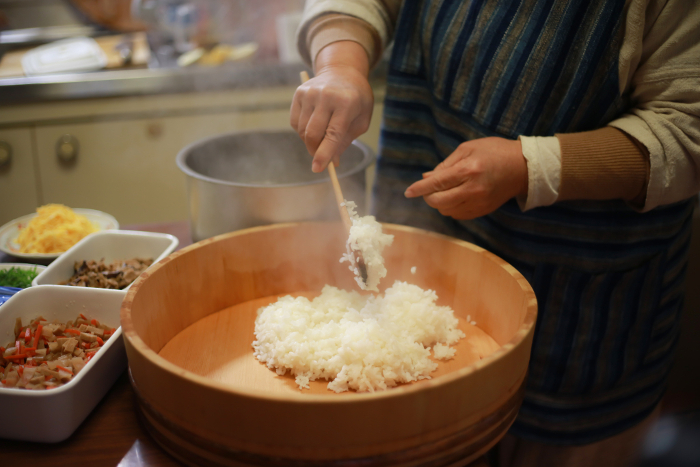 A woman making chirashi-sushi in her hand