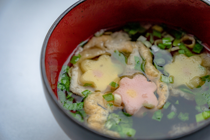 clear broth soup, with ingredients and garnish floating in and on it