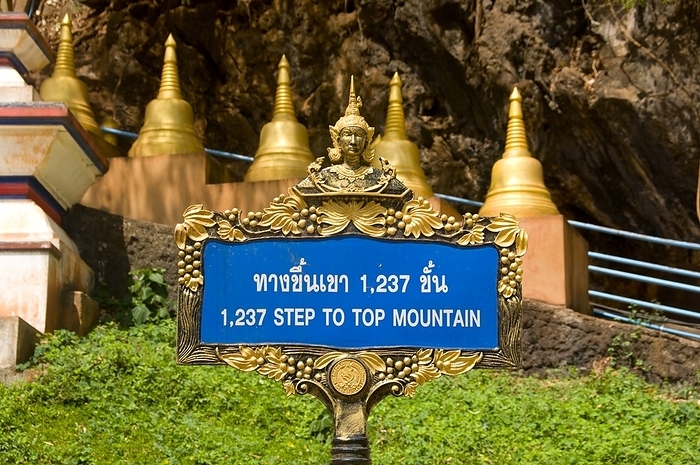 Thailand: Sign indicating how many steps there are to the summit, Wat Tham Seua, Krabi Town, Krabi Province, Southern Thailand Wat Tham Seua, the  Temple of the Tiger Cave  is built into a cave set in a limestone cliff. br   br    Surrounded by individual monk s residences, this is one of southern Thailand s best known forest temples. br   br    The main viharn or assembly hall extends into a long, shallow limestone cave displaying various grim reminders of mortality as a counterbalance to worldly desires. At the back of the cave a flight of marble stairs lead up to the  tiger cave  itself. Within there is a venerated Buddha footprint on a gilded platform and a life size figure of Ajaan Jamnien, the temple s enigmatic abbot. br   br    The sprawling temple grounds are partly landscaped, and there are two separate stairways leading to a large Guan Yin image  the Mahayana Buddhist version of the Indian sage Avalokitesvara, known generally as  the Chinese Goddess of Mercy  , and to another Buddha footprint.