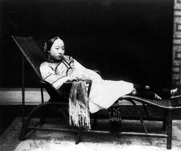 China: A young woman with bound feet reclining on a chaise longue, c.1890 Foot binding  pinyin: chanzu, literally  bound feet   was a custom practiced on young girls and women for approximately one thousand years in China, beginning in the 10th century and ending in the first half of 20th century. br   br    There is little evidence for the custom prior to the court of the Southern Tang dynasty in Nanjing, which celebrated the fame of its dancing girls, renowned for their tiny feet and beautiful bow shoes. What is clear is that foot binding was first practised among the elite and only in the wealthiest parts of China, which suggests that binding the feet of well born girls represented their freedom from manual labor and, at the same time, the ability of their husbands to afford wives who did not need to work, who existed solely to serve their men and direct household servants while performing no labor themselves. br   br    Bound feet were considered intensely erotic in traditional Chinese culture. Qing Dynasty sex manuals listed 48 different ways of playing with women s bound feet. Some men preferred never to see a woman s bound feet, so they were always concealed within tiny  lotus shoes  and wrappings. Feng Xun is recorded as stating,  If you remove the shoes and bindings, the aesthetic feeling will be destroyed forever    an indication that men understood that the symbolic erotic fantasy of bound feet did not correspond to its unpleasant physical reality, which was therefore to be kept hidden. br   br    For men, the primary erotic effect was a function of the lotus gait, the tiny steps and swaying walk of a woman whose feet had been bound. 