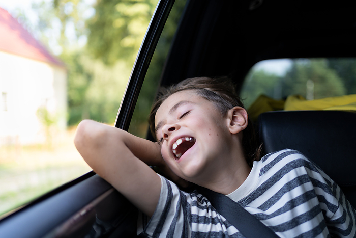 A young boy is traveling by car and enjoys the warm wind from an open window A young boy is  enjoys the warm wind from an open car windowdow