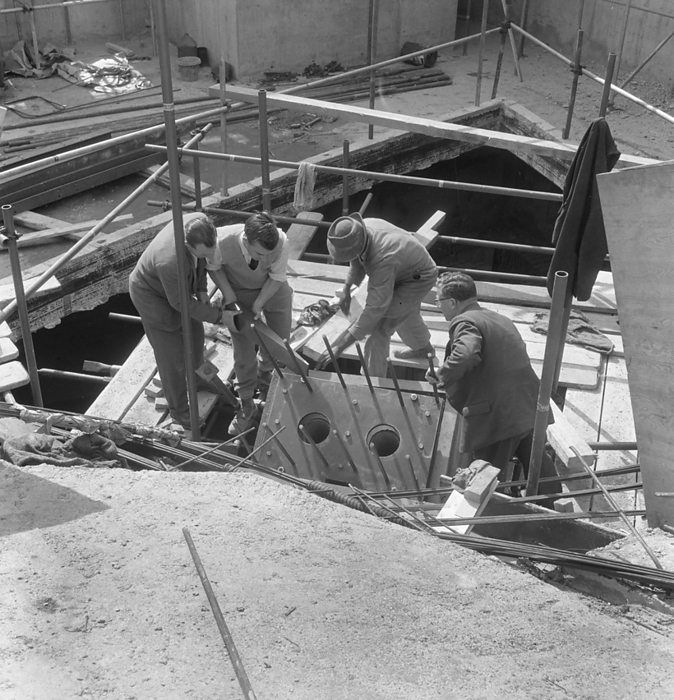 Commonwealth Institute, Kensington High Street, Kensington, London, 07 09 1961. Creator: John Laing plc. Commonwealth Institute, Kensington High Street, Kensington, London, 07 09 1961. Workers inserting a wedge in the timber formwork at the top of a roof support column during construction of the Commonwealth Institute exhibition hall. Laing built the Commonwealth Institute between October 1960 and October 1962 to replace the former Imperial Institute that was to be demolished to make way for new facilities at Imperial College.  The building  consisted of a four storey administrative block housing a library, restaurant, board room and conference hall and a separate two storey block containing a cinema with an art gallery above, but the focus of the project was the exhibition hall with its hyperbolic paraboloid roof, the first of its kind constructed in Great Britain.  The exhibition, designed by James Gardner, provided spaces where each of the Commonwealth nations could showcase their achievements and characteristics, primarily to school children as teaching aids to enliven history and geography lessons. The shell arch of the central roof section was of reinforced concrete, cast in situ using timber formwork with rough sawn boards to provide a textured internal surface whilst the four outer  quot warps quot  were constructed using precast beams and wood wool slabs, blocks of shredded timber bound together in a cement paste and left visible from the interior.  The entire roof was then clad in copper sheeting over a layer of vermiculite.  It covers an area of 33,700sqft, 183 feet square with the central section 93 feet square and ranges between 30ft high at its lowest and 80ft at the peaks.