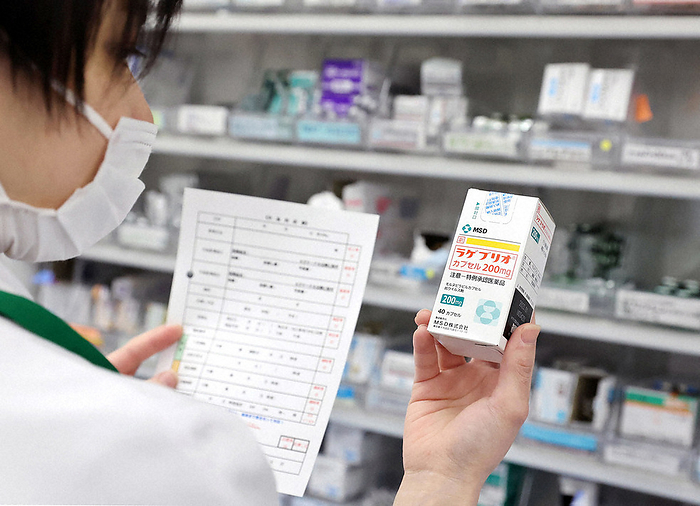 A pharmacist holding the oral drug mornupiravir, which was approved as a special exception late last year. A pharmacist holds the oral drug mornupiravir, which was approved as a special exception late last year, in Toshima Ward, Tokyo, January 1, 2022. Photo by Kentaro Ikushima