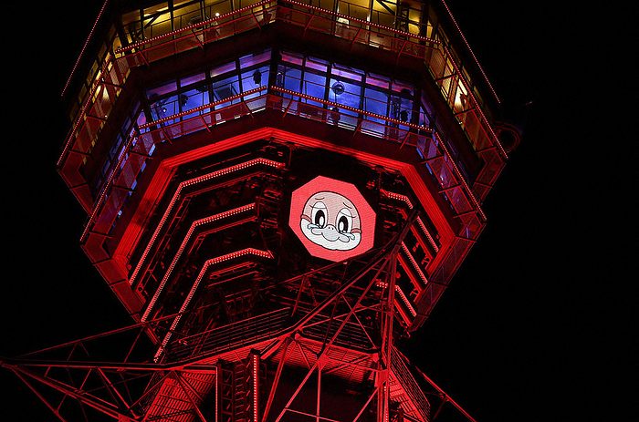 Tsutenkaku Tower is lit up in red according to Osaka Prefecture s own  Osaka Model  warning standard for the spread of the new coronavirus. In the center is Osaka Prefecture s official mascot character  Mozuyan. Tsutenkaku Tower lit up in red according to Osaka Prefecture s own  Osaka Model  warning standard for the spread of the new coronavirus. In the center is Osaka Prefecture s official mascot character  Mozuyan  in Naniwa Ward, Osaka City, on the afternoon of January 24, 2022. Photo by Hiroki Takikawa, 6:16 p.m.