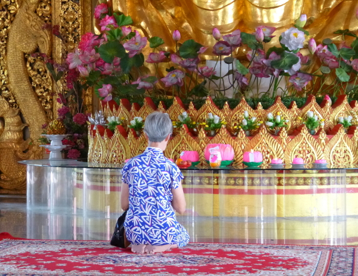 An old woman praying at a temple, back view, George Town, Penang Island.