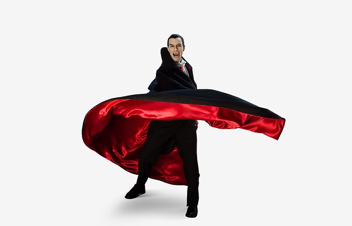 masculine gender Portrait of a man dressed as a vampire against a white background quickly turning away from camera moving his cape with him