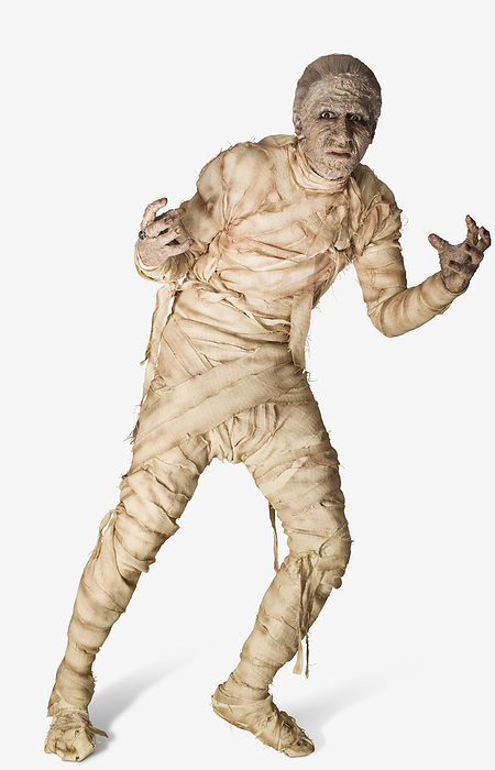 Man dressed up as a mummy for Halloween, making a stiff movement away from camera, against a white background