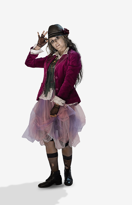 Woman dressed in Zombie Halloween costume tipping her hat at camera while making a face, against a white background
