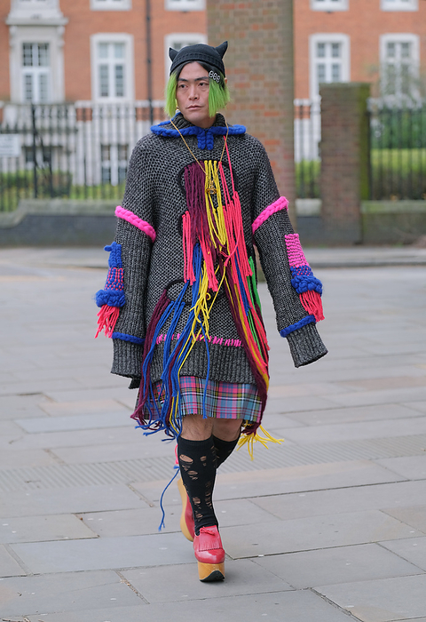 Fall Winter 2022 23 London Street Snapshot Street style on day 4 of London Fashion Week on Monday 21st February 2022. Stylish individuals are seen arriving to their shows or presentations. Image shows flamboyant Japanese Journalist Yu Masui. He wears a long knitwear sweater by Roksanda ilincic, with a tartan skirt or kilt and shoes both by Vivienned Westwood. 