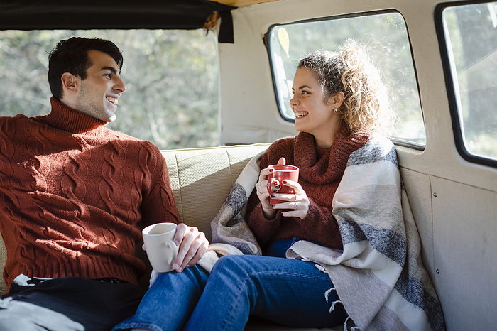 Castellina in Chianti, Siena, Tuscany, Italy, young couple drinking coffee inside campervan during trip in the forest, togetherness, freedom, love Happy couple having coffee in van on weekend, Photo by Emma Innocenti