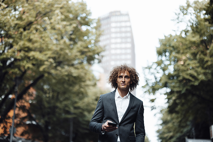 Businessman holding mobile phone in city, Photo by Gustafsson