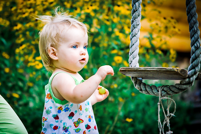 child Cute baby girl 3 4 year old in the garden plays a rustic swing, Krasnodar, Krasnodar Krai, Russia
