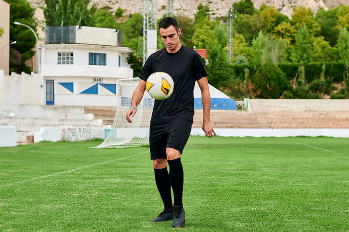 A football player touches a soccer ball on a soccer field, Villena, Valencian Community, Spain