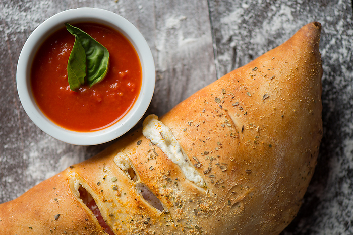 Calzone with marinara sauce over a wood with flour, Miami, FL, United States