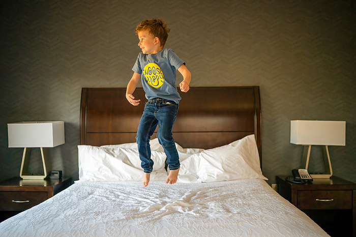 Happy boy jumping on a hotel bed, Arlington, Virginia, United States