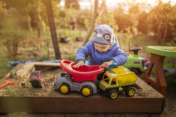 Small boy playing with toys in sandpit wearing blue clothes, Gryfino, West Pomeranian Voivodeship, Poland