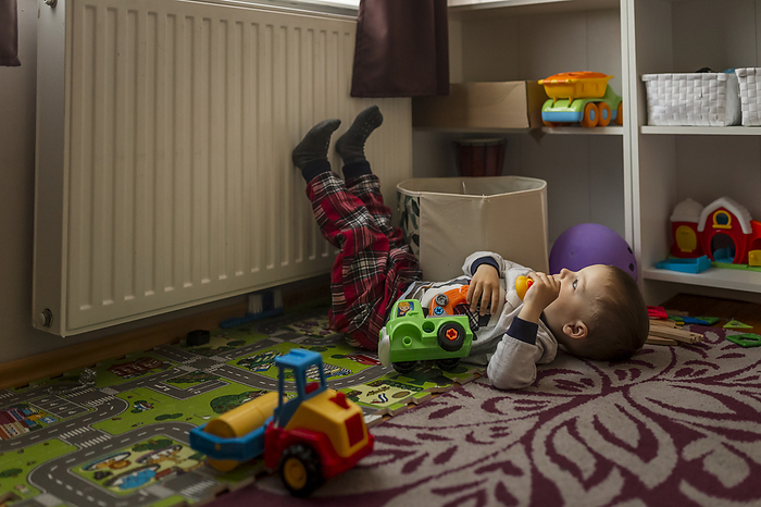 Small blonde boy in his room lying down on the floor and playing, Gryfino, West Pomeranian Voivodeship, Poland