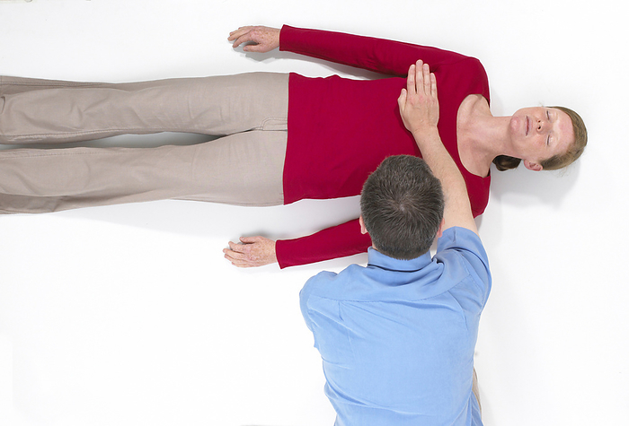 First aid First aid, step by step guide to CPR, woman lying on back simulating unconsciousness, man with one palm flat across woman s chest., Photo by DK IMAGES SCIENCE PHOTO LIBRARY
