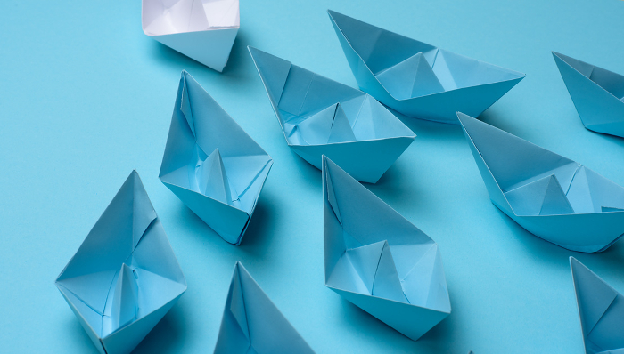 group of blue paper boats follow white against a light blue background. Strong leader concept, mass manipulation. Starting a business with a well coordinated team, start up group of blue paper boats follow white against a light blue background. Strong leader concept, mass manipulation. Starting a business with a well coordinated team, start up