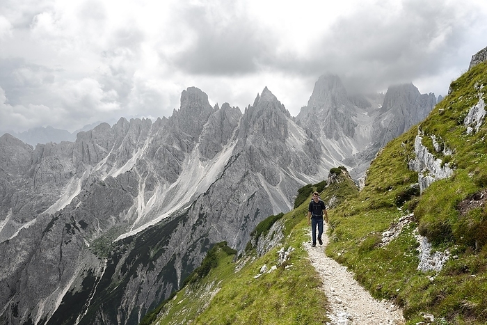 Italy Hikers on a trail, mountain peaks and pointed rocks in the background, dramatic cloudy sky, Cimon di Croda Liscia and Cadini group, Auronzo di Cadore, Belluno, Italy, Europe, Photo by Mara Brandl