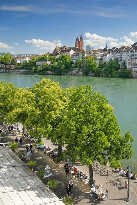 Basel, Switzerland View from the river promenade of Basel Cathedral and the old town of Basel with the turquoise Rhine River and the lively river promenade in the foreground